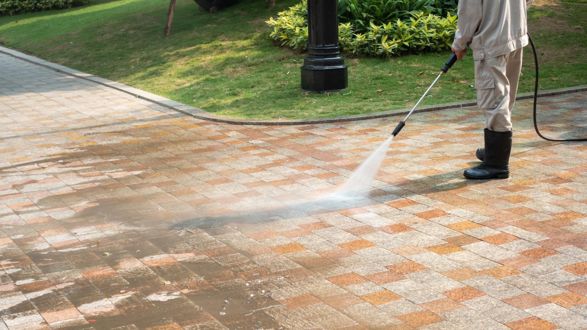 professional in black boots pressure washing concrete