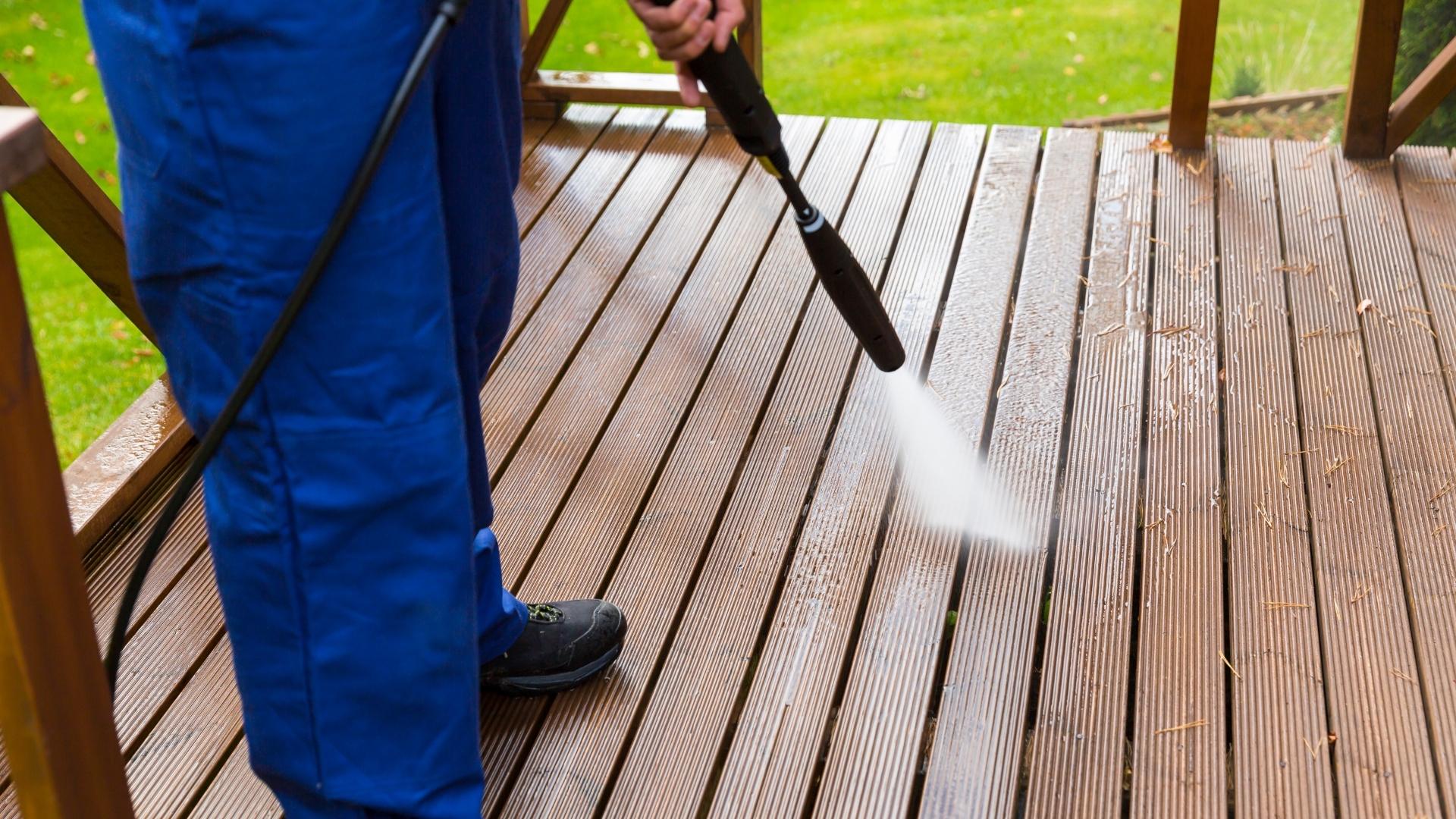 professional in blue uniform pressure washing deck