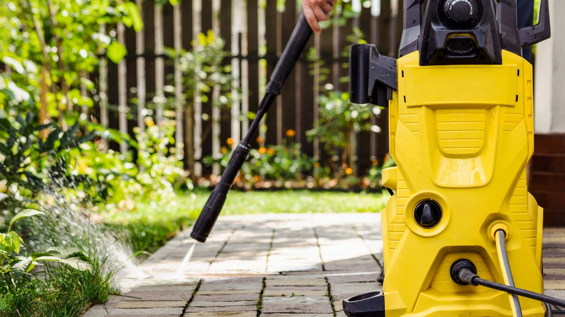 professional with yellow pressure washer pressure washing concrete